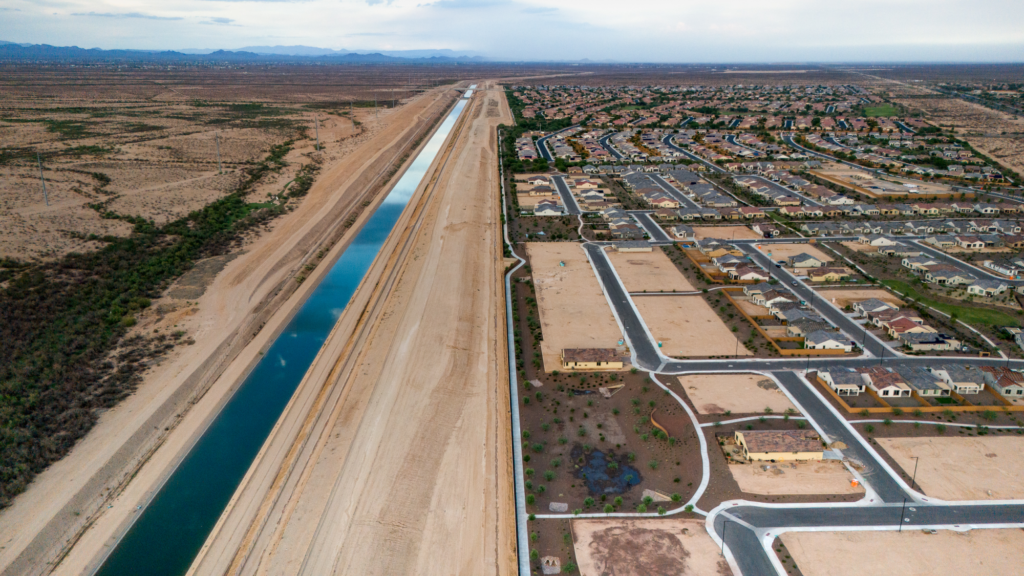 An eastward aerial view of houses under construction in the Festival Ranch neighborhood in Buckeye, Arizona. The Central Arizona Project canal runs southwest and abuts undeveloped desert. Caitlin O'Hara / High Country News